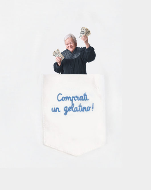 Dettaglio della T-Shura maglietta con nonna nel taschino che dà soldi mancetta e dice "Comprati un gelatino!" le magliette dei nipoti, la frase dei nonni è ricamata in azzurro t-sciura