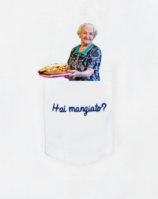Dettaglio della T-Shura maglietta con nonna che ha cucinato nel taschino che chiede "Hai mangiato?" le magliette delle nonne, la frase dei nonni è ricamata in blu
